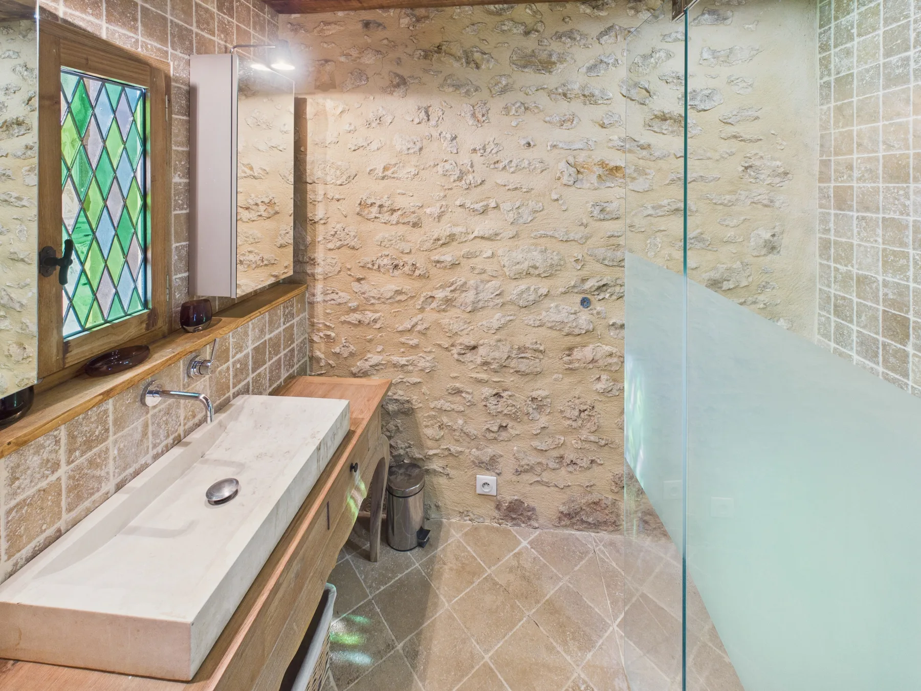 A bathroom with a long vanity beside a glass shower.