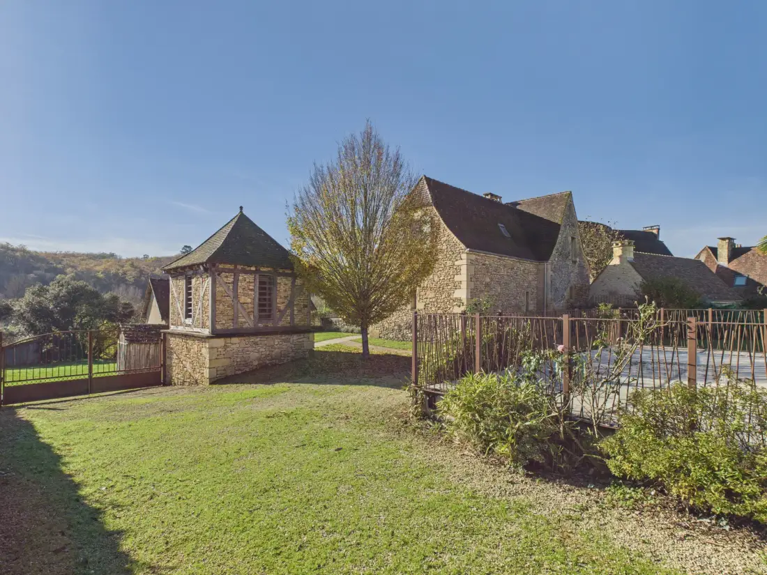 Stone buildings and a small turret stand beside a grassy garden.
