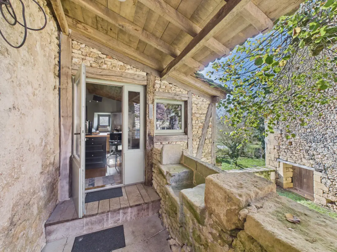 A covered stone patio with a glass door opening into the house.