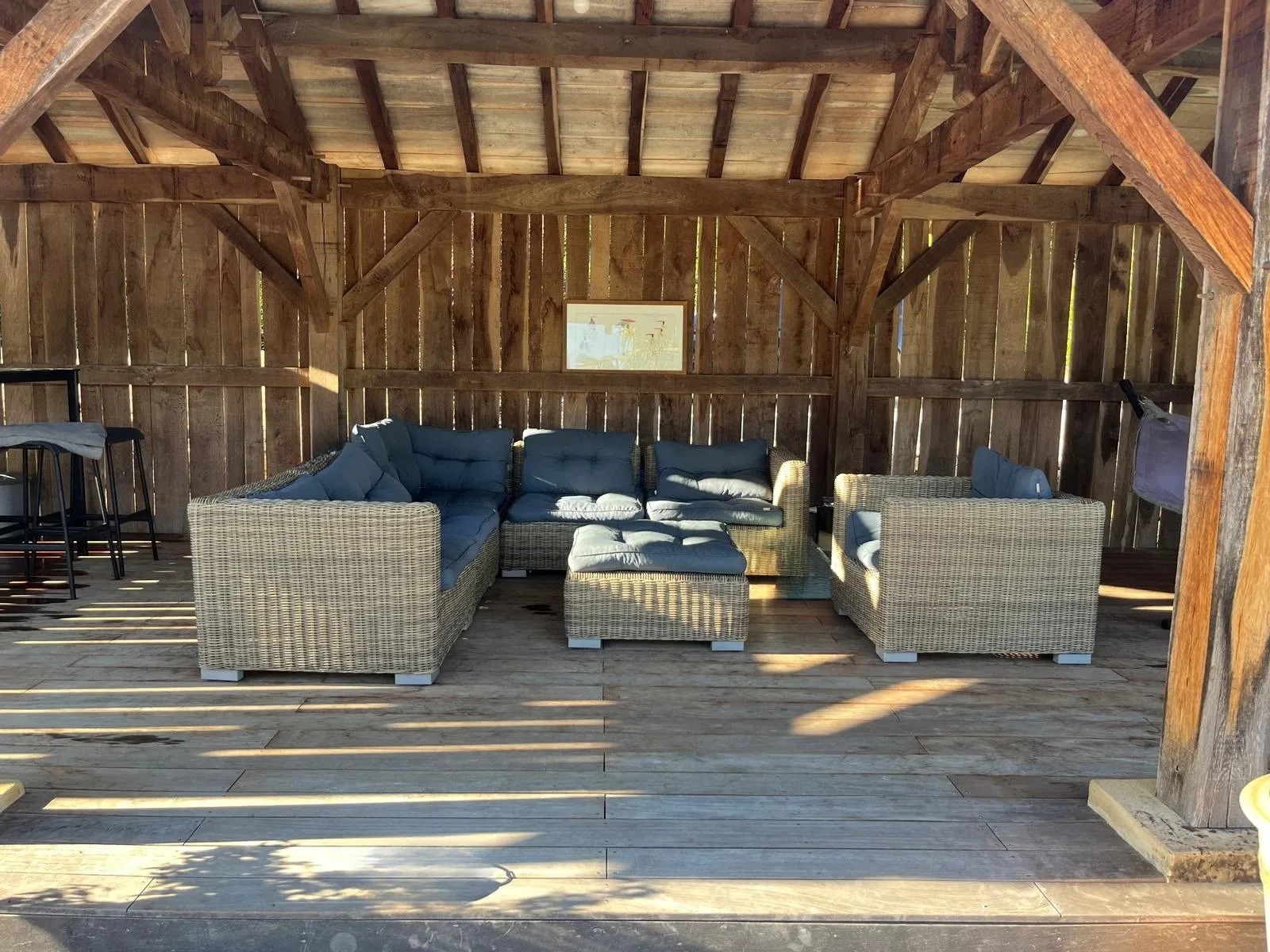 A covered wooden seating area with cushioned outdoor furniture.
