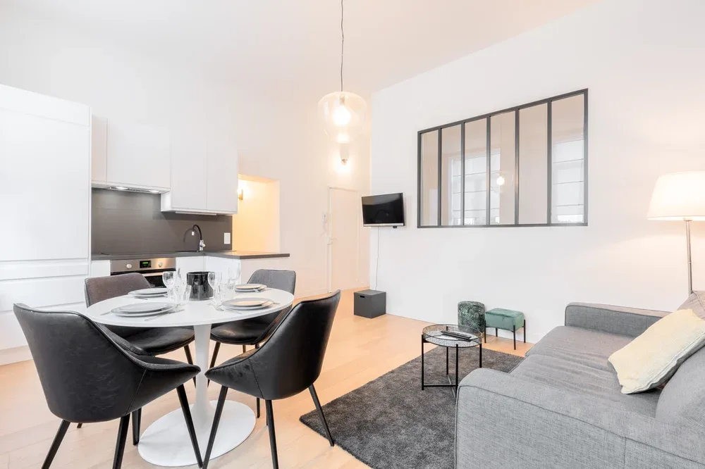 A bright open-plan living and dining area with a kitchen and gray seating.