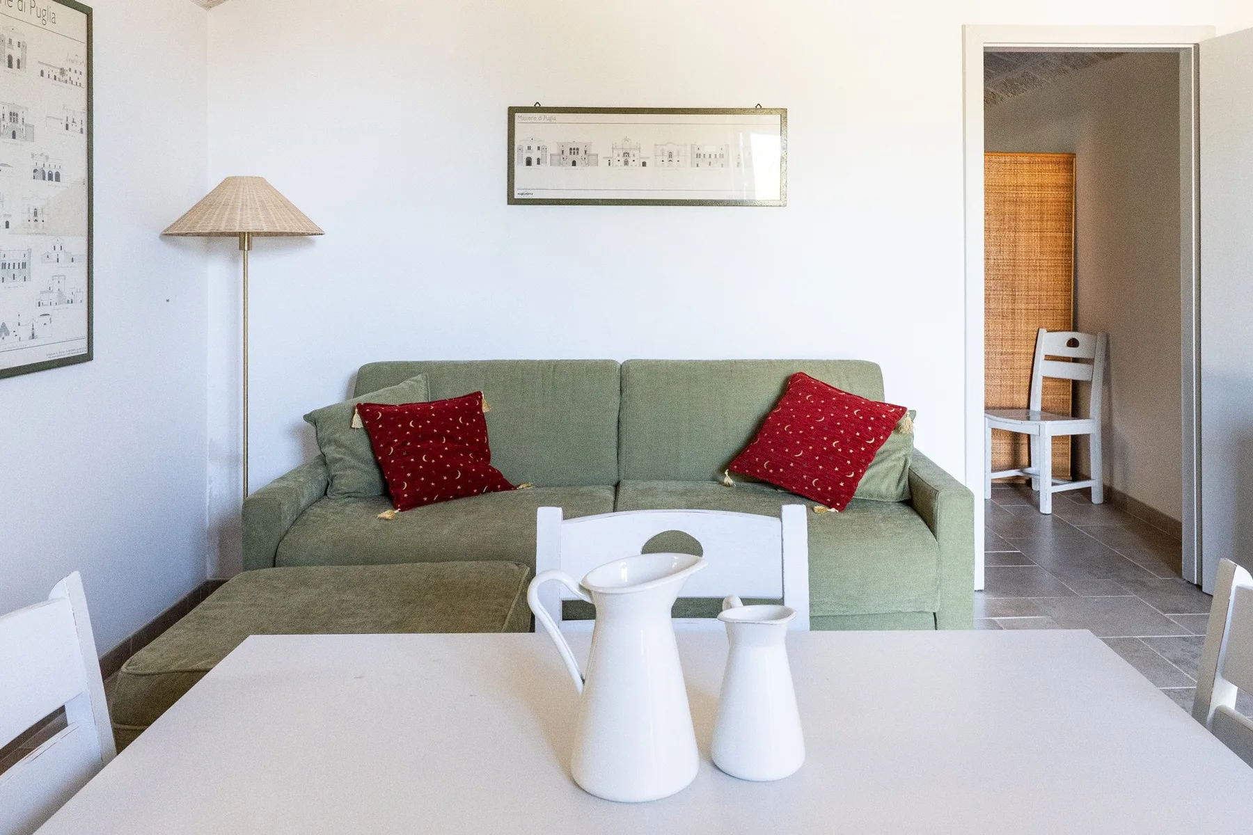A living room with a green sofa and a white table in the foreground.