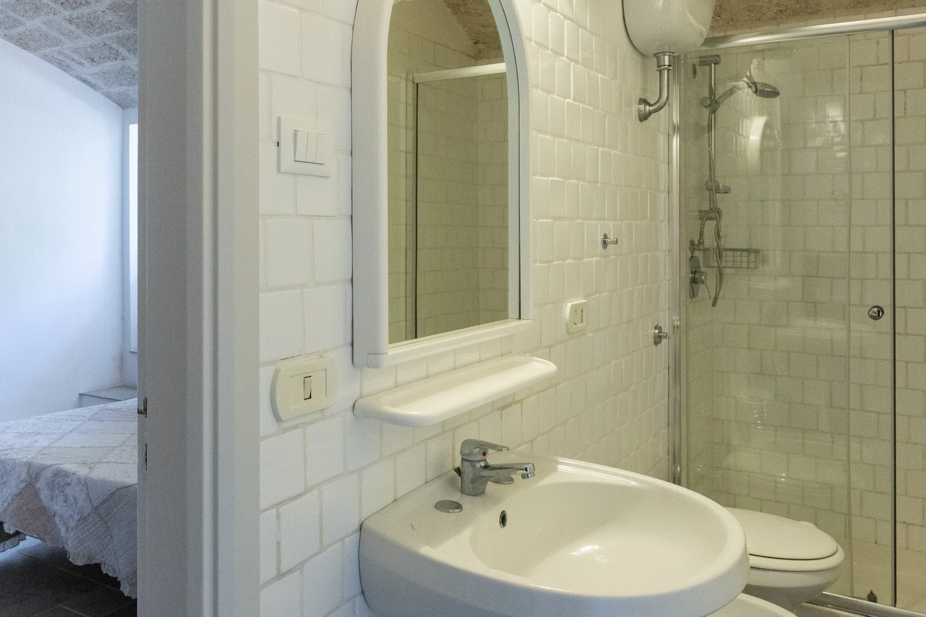 A tiled bathroom with a sink, mirror, and shower.