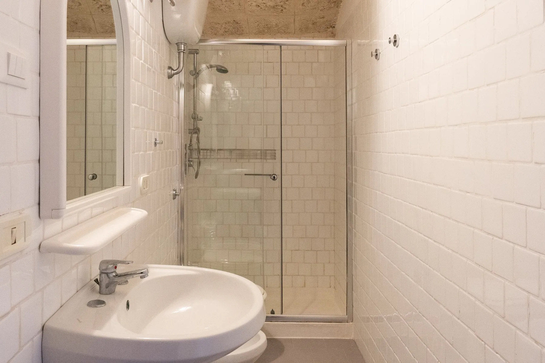 A tiled bathroom with a sink and glass shower.