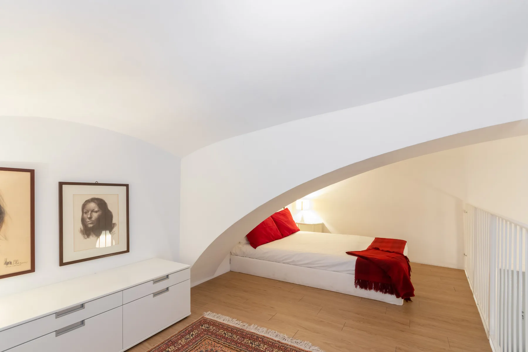 A bedroom with a bed tucked beneath a sloped ceiling and framed art on the wall.