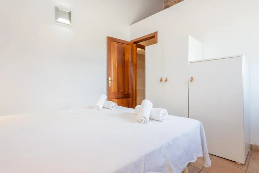 A bedroom with a neatly made bed and an open wooden door.