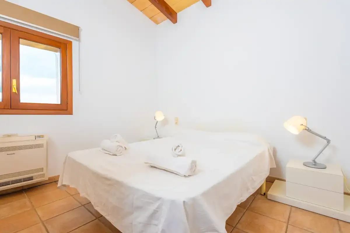 A bedroom with a bed, bedside table, and window.