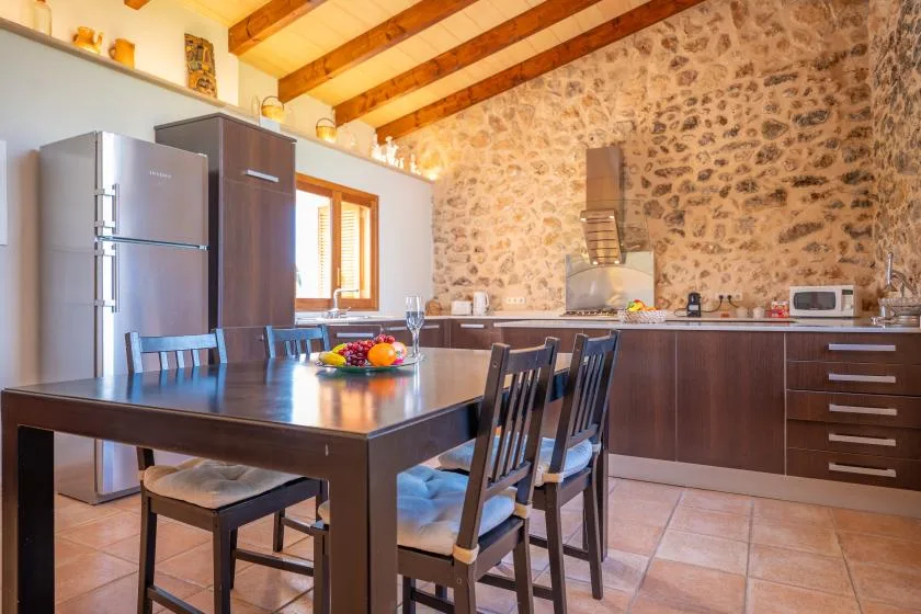 A kitchen and dining area with a table set with fruit.