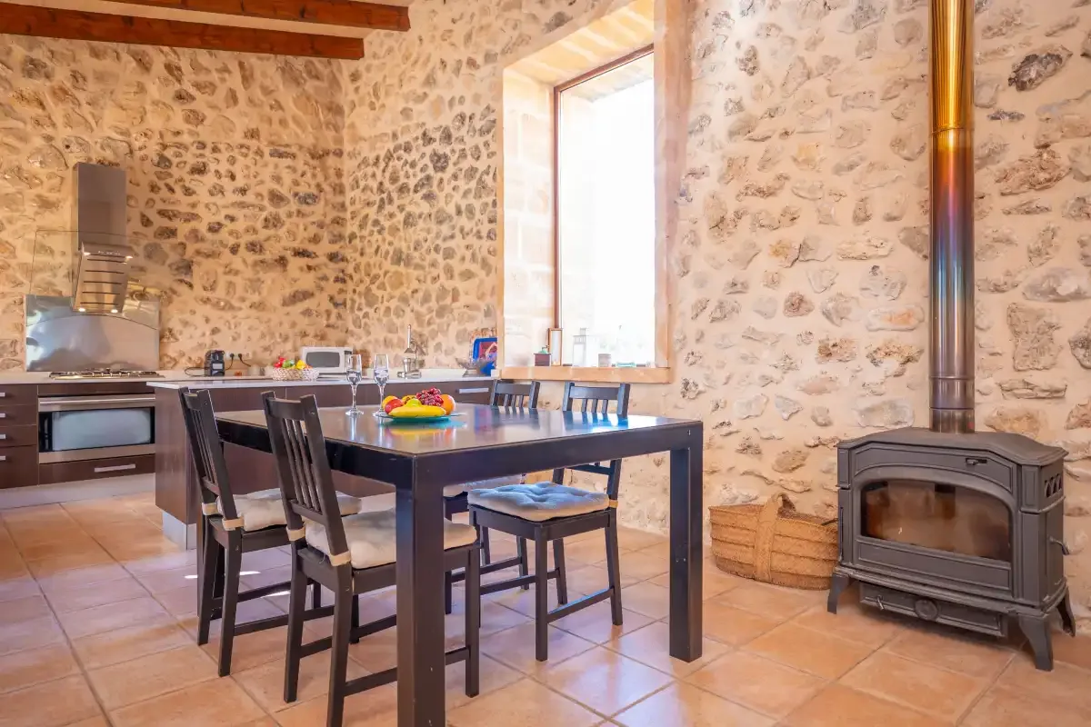 A dining area with a dark table and chairs beside a kitchen.