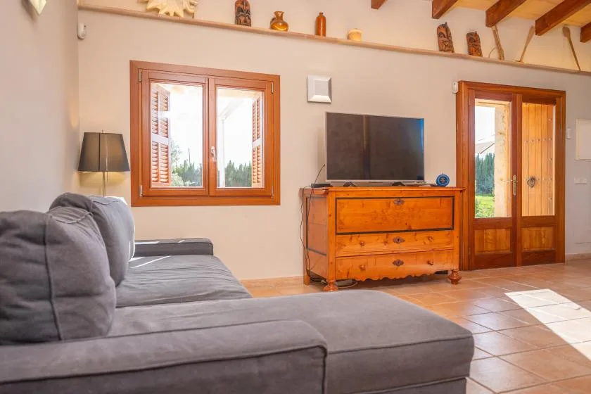 A living room with gray seating, a television, and a wooden cabinet.