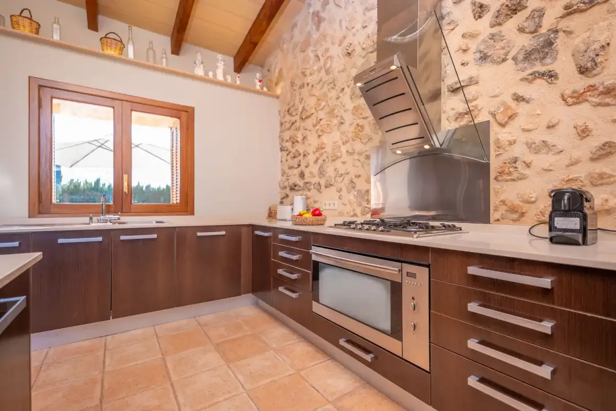 A kitchen with dark wood cabinets, a stone wall, and a large oven.