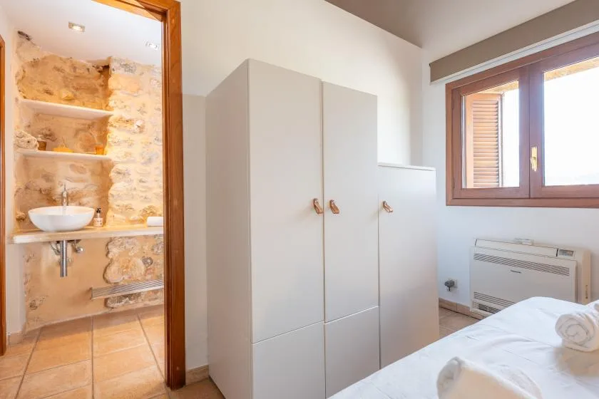 A bedroom with white storage cabinets, a window, and an adjoining bathroom.