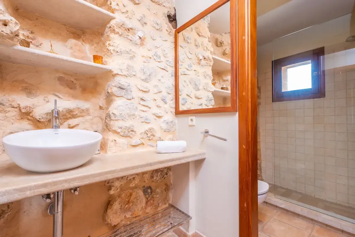 A bathroom vanity with a vessel sink sits beside a tiled shower.