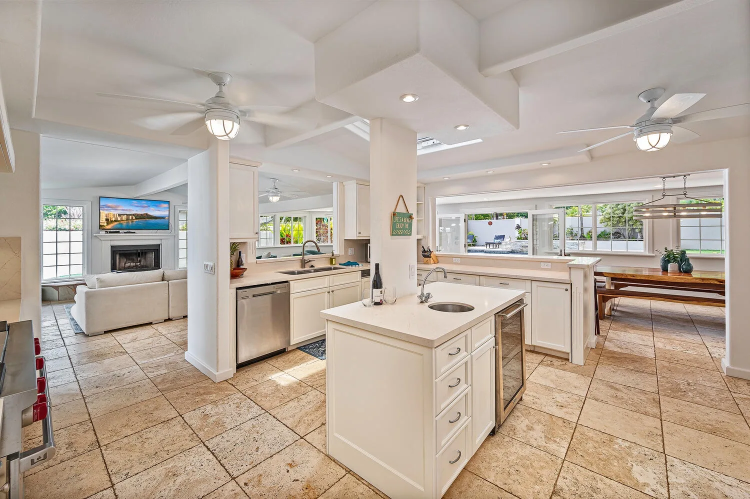 Una cocina luminosa y abierta con una isla central y una sala al fondo.
