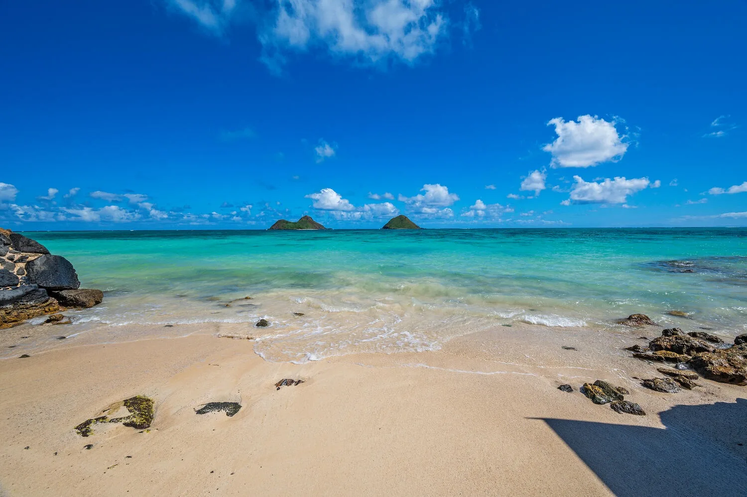Una playa de arena se encuentra con aguas turquesas y un cielo azul despejado.