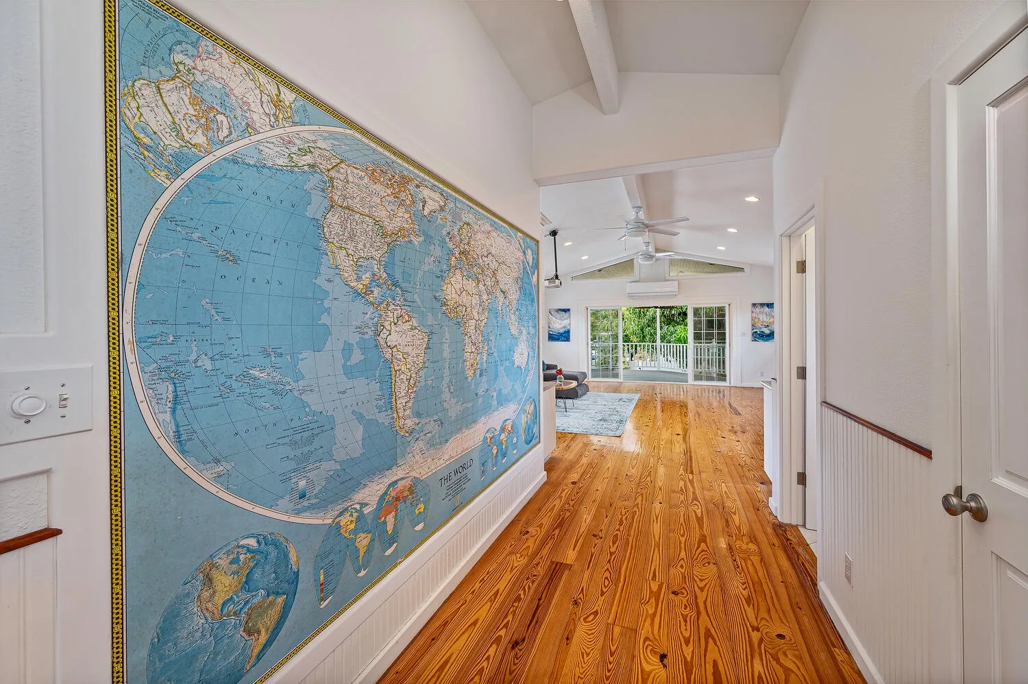 Un pasillo con un gran mapa del mundo en la pared conduce a una habitación luminosa.
