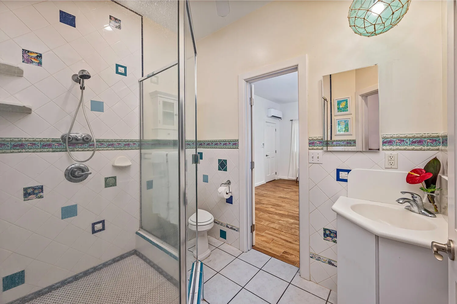 Un baño alicatado con ducha de cristal, inodoro y lavabo.