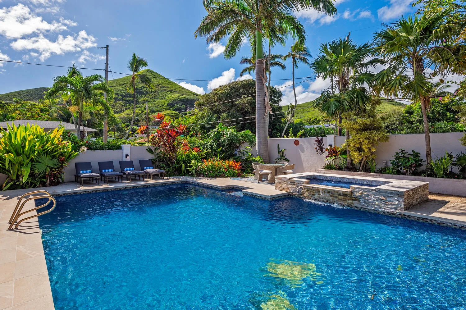 Una piscina está rodeada de plantas tropicales y asientos junto a la piscina.