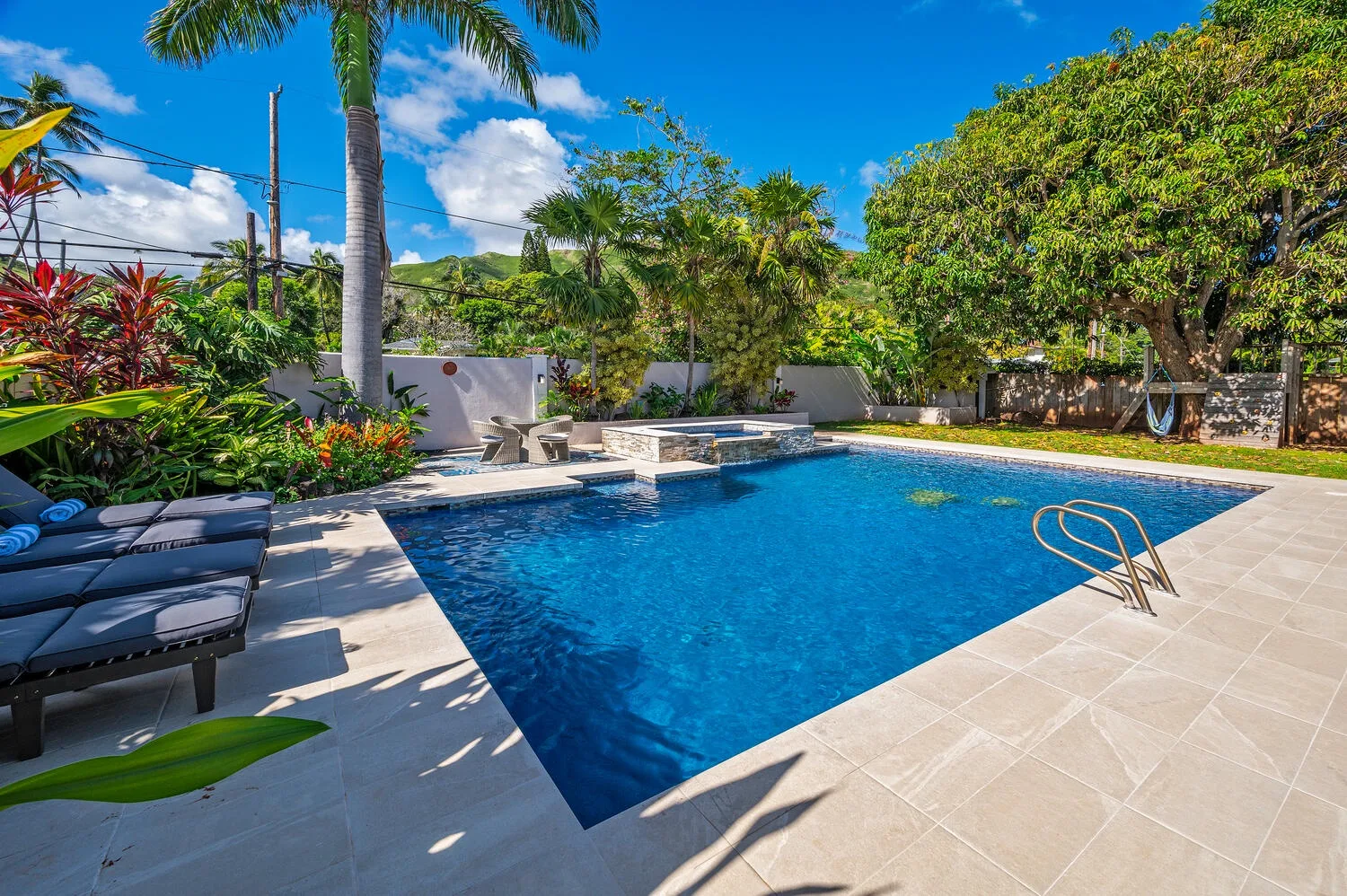Una piscina rodeada de plantas tropicales, con asientos junto a la terraza.