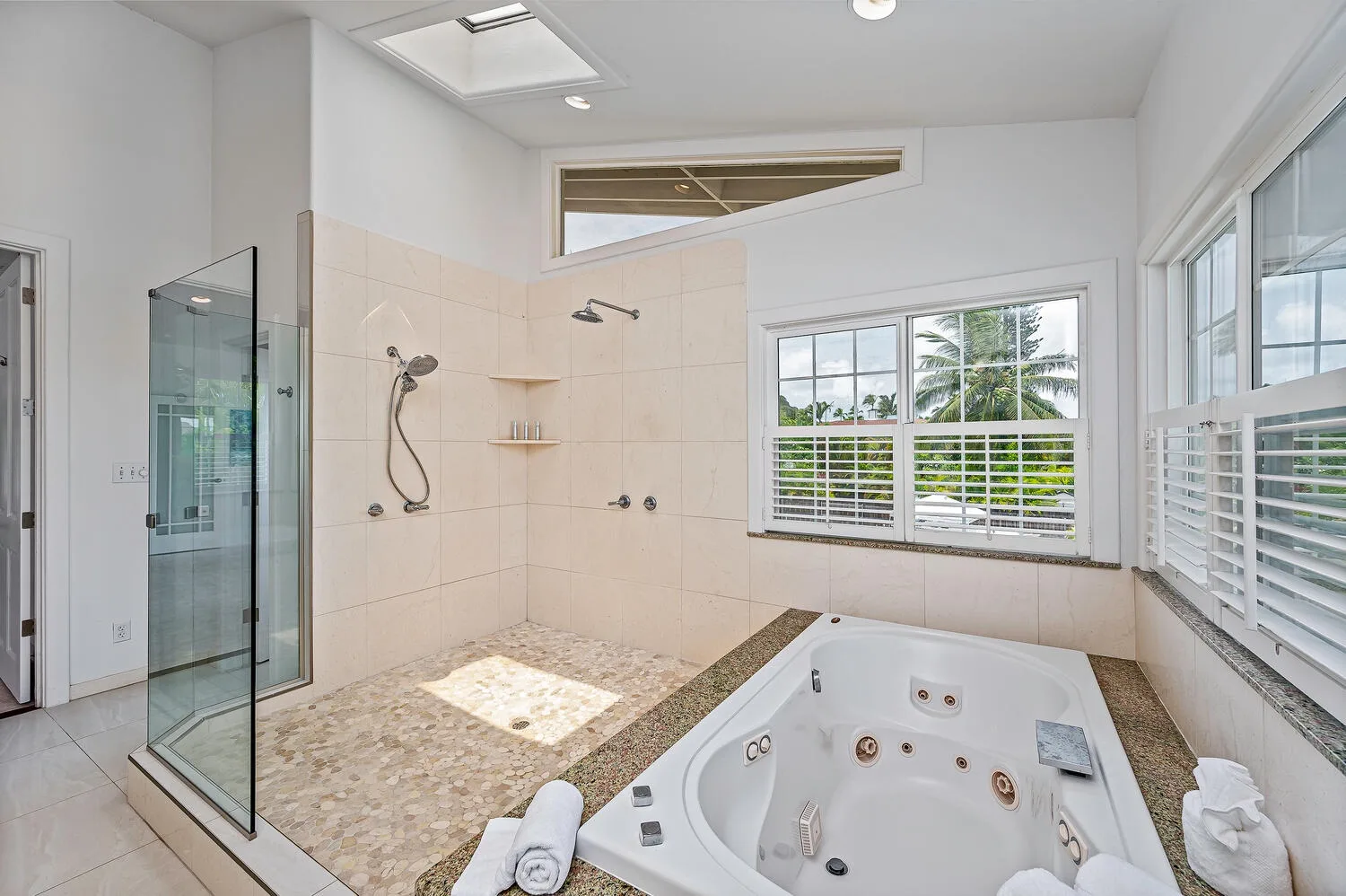 Un baño luminoso con bañera empotrada, ducha y ventanas grandes.