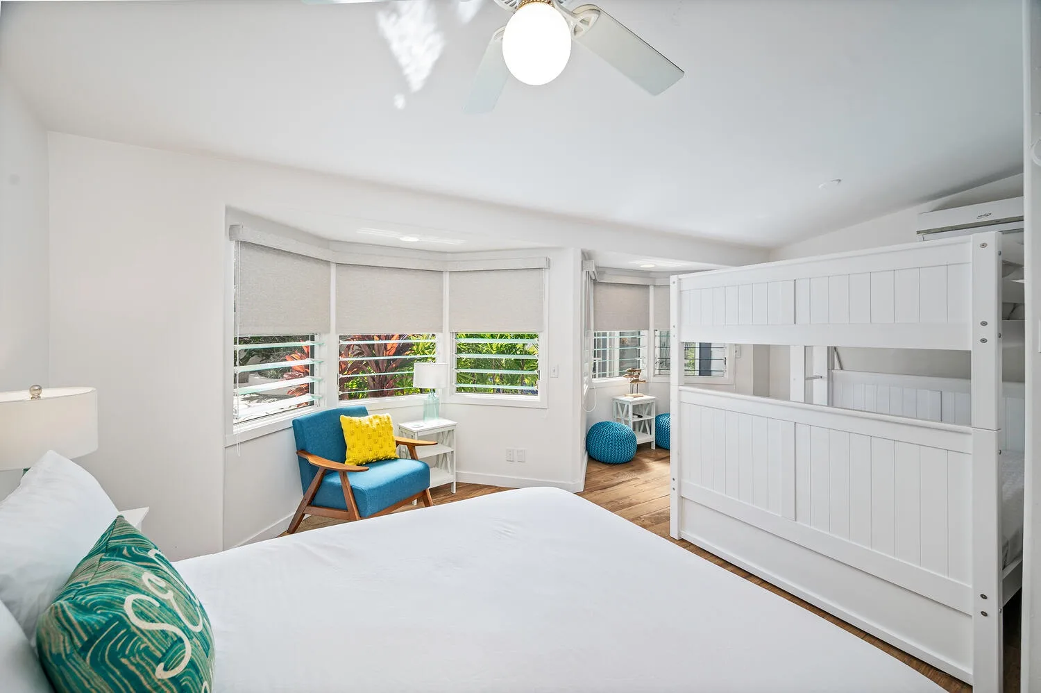 Dormitorio luminoso con una cama, una ventana y una pequeña zona de estar.