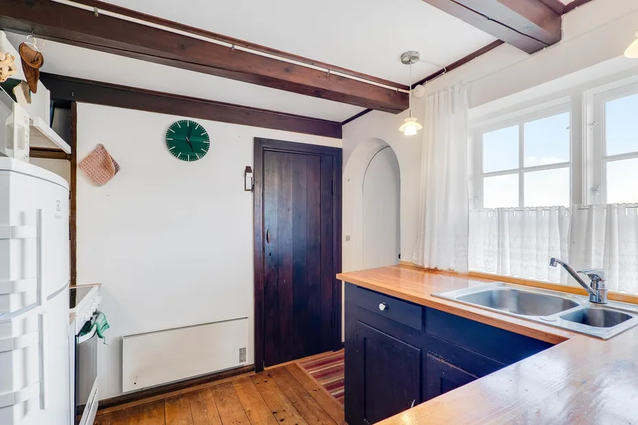 A bright kitchen with a central island, sink, and large windows.