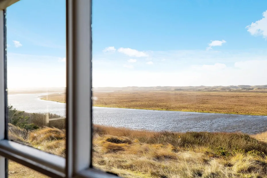 A river winds through open grassland beyond a window.