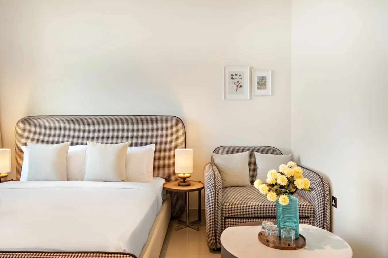Un dormitorio con una cama junto a un sillón acolchado y una mesita.