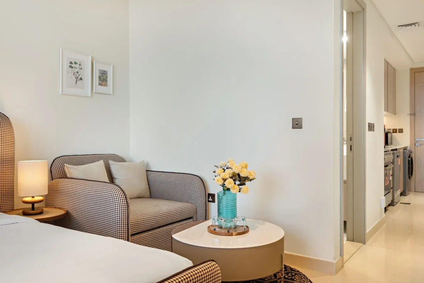 Una zona de estar en el dormitorio tiene asientos estampados, una mesa redonda y flores.