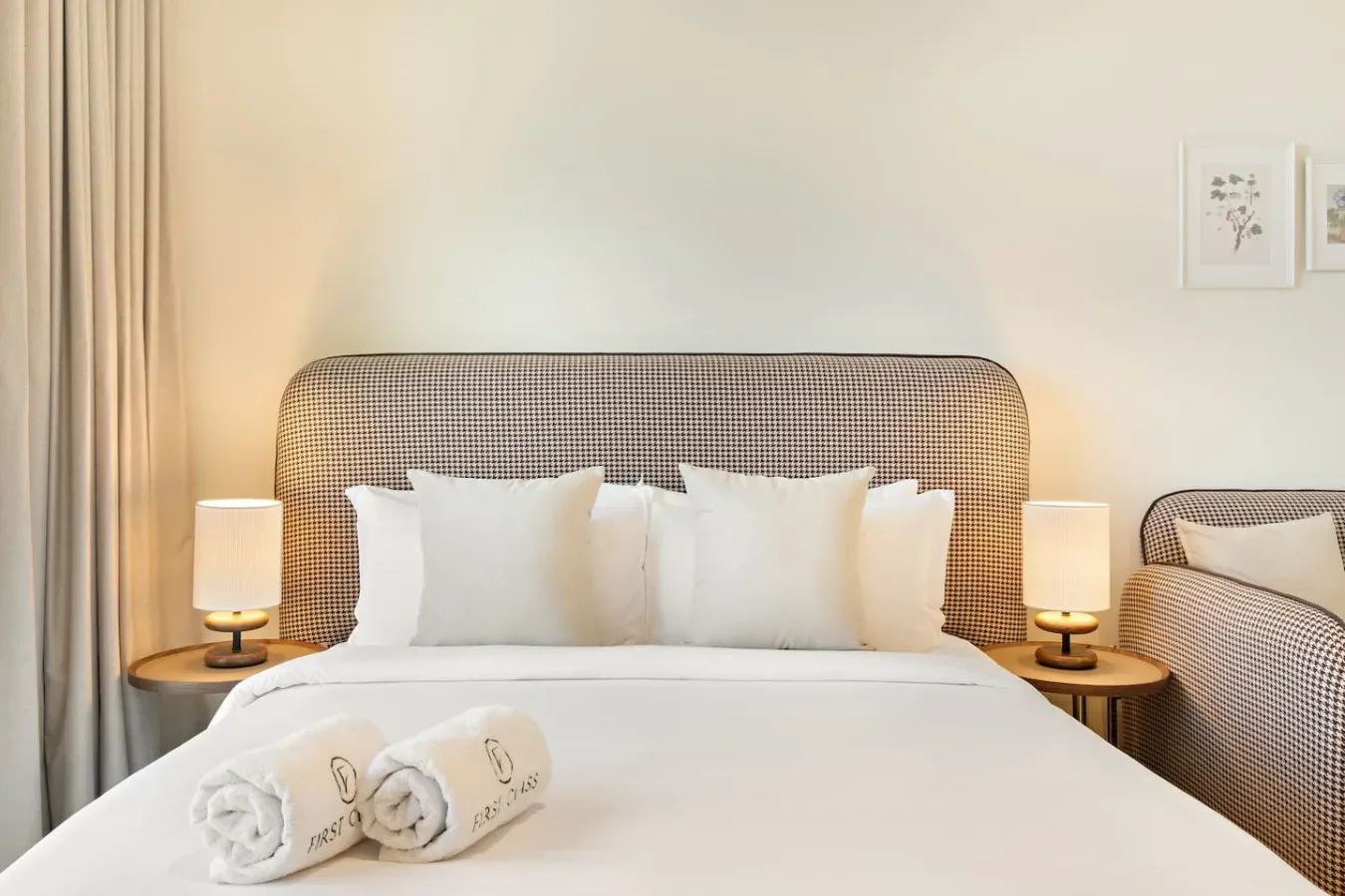 Un dormitorio ordenado con una cama de ropa blanca y lámparas de noche.