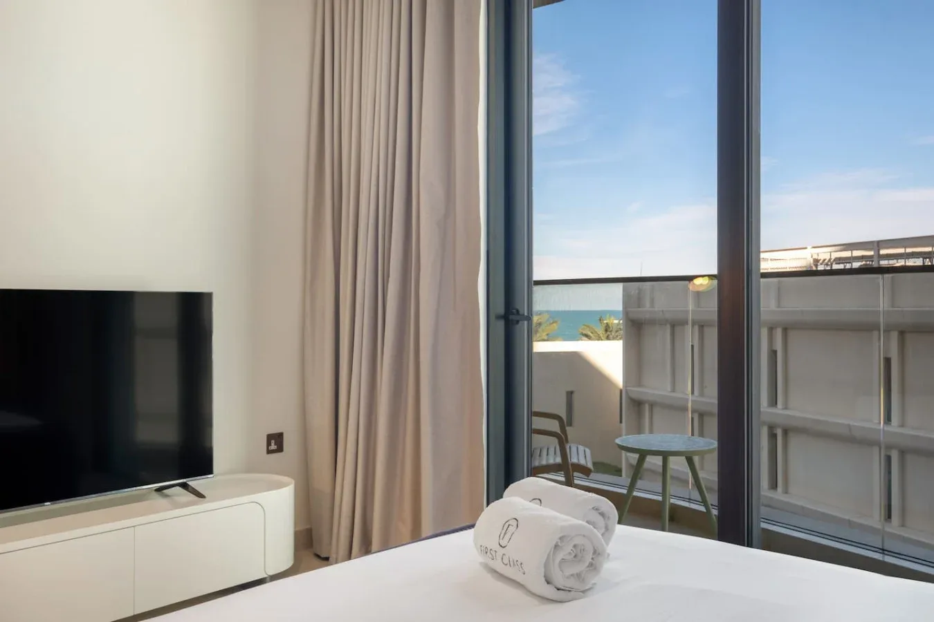 Un dormitorio con un televisor junto a cortinas y puertas de vidrio que dan a un balcón.