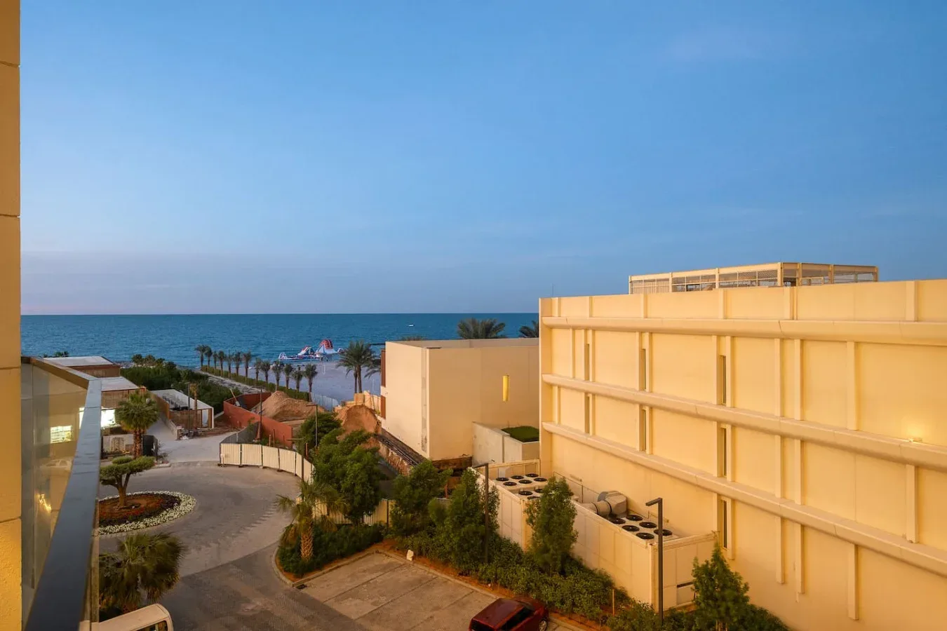 Una escena de complejo costero con vistas al mar, jardines y edificios modernos.