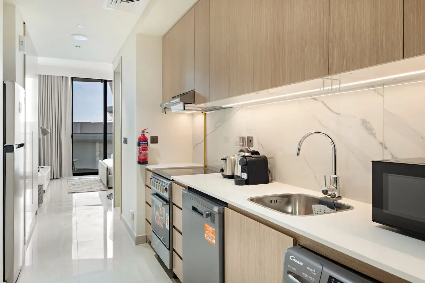 Una cocina moderna con gabinetes de madera clara, una encimera y un fregadero de acero inoxidable.