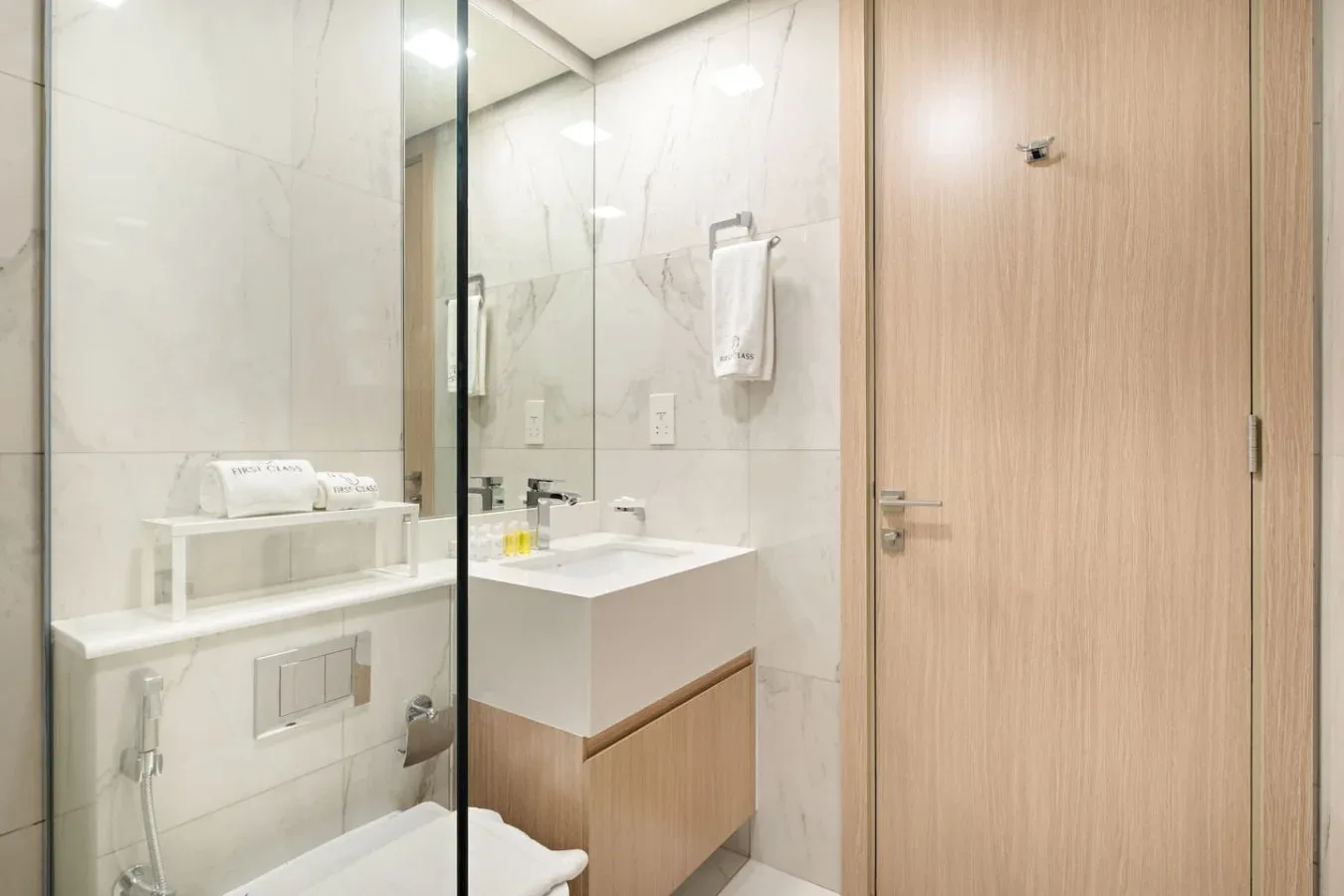 Un baño con lavabo, espejo y una puerta de madera cerrada.