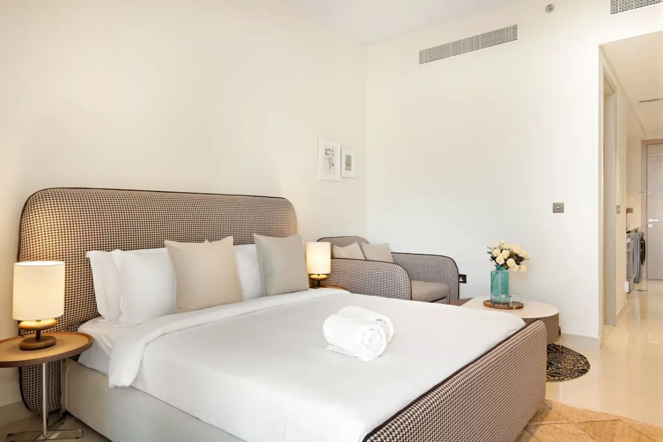 Un dormitorio luminoso con una cama tendida y una zona de estar.