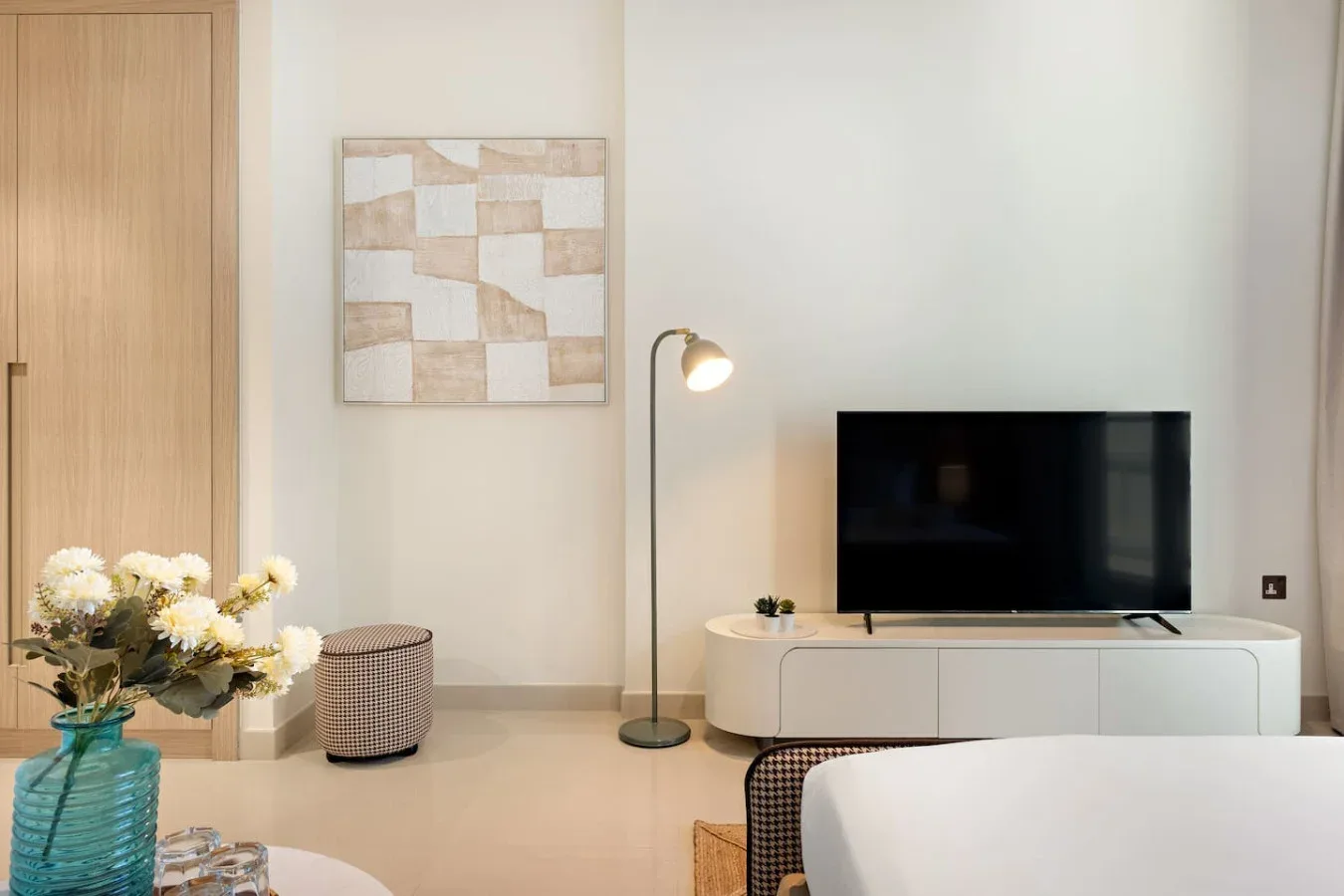 Una sala de estar con un televisor sobre un mueble bajo y una lámpara de pie.
