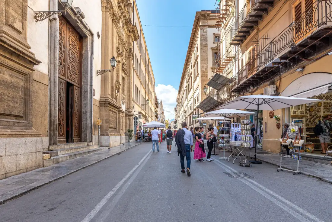 A pedestrian street lined with historic buildings and outdoor market stalls.