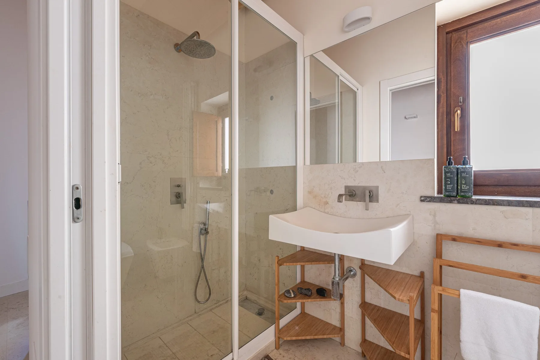 A bathroom with a glass shower and a white sink beneath a mirror.