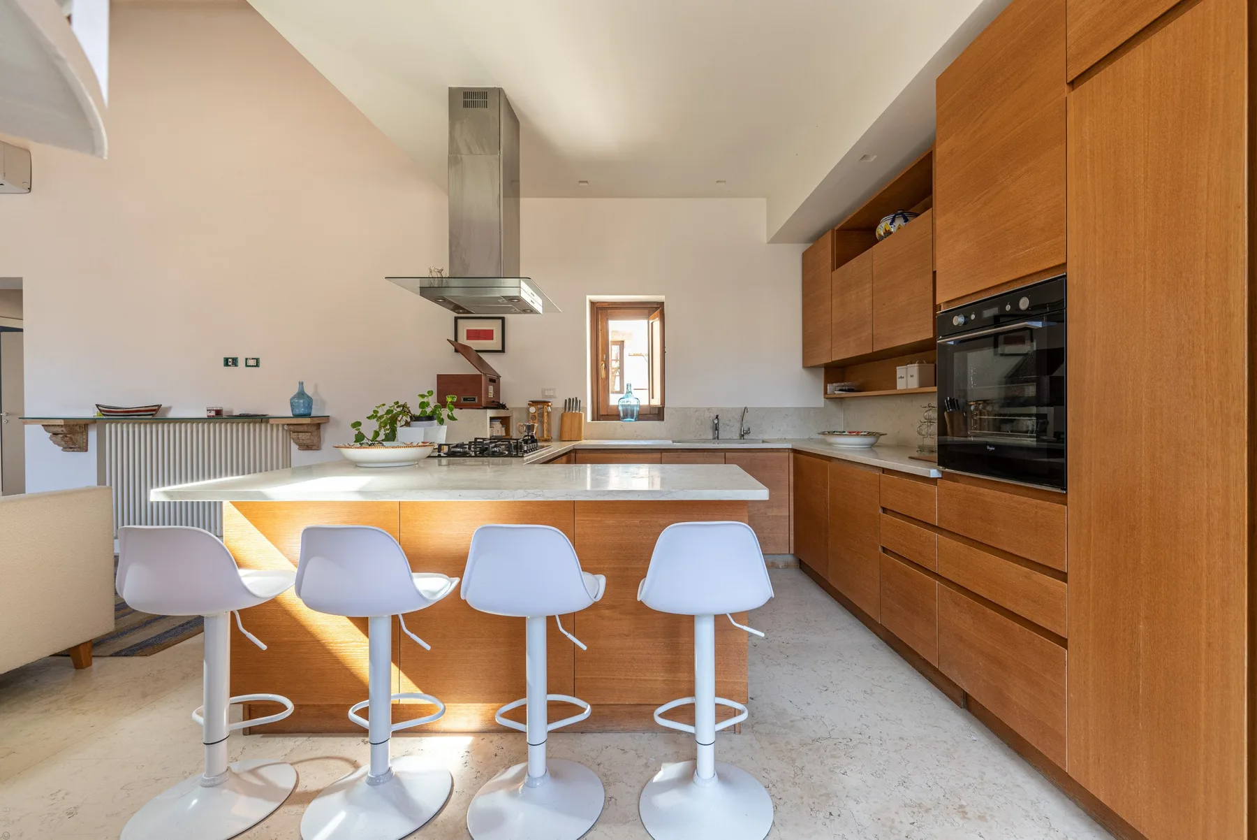 A modern kitchen with a central island and four stools.