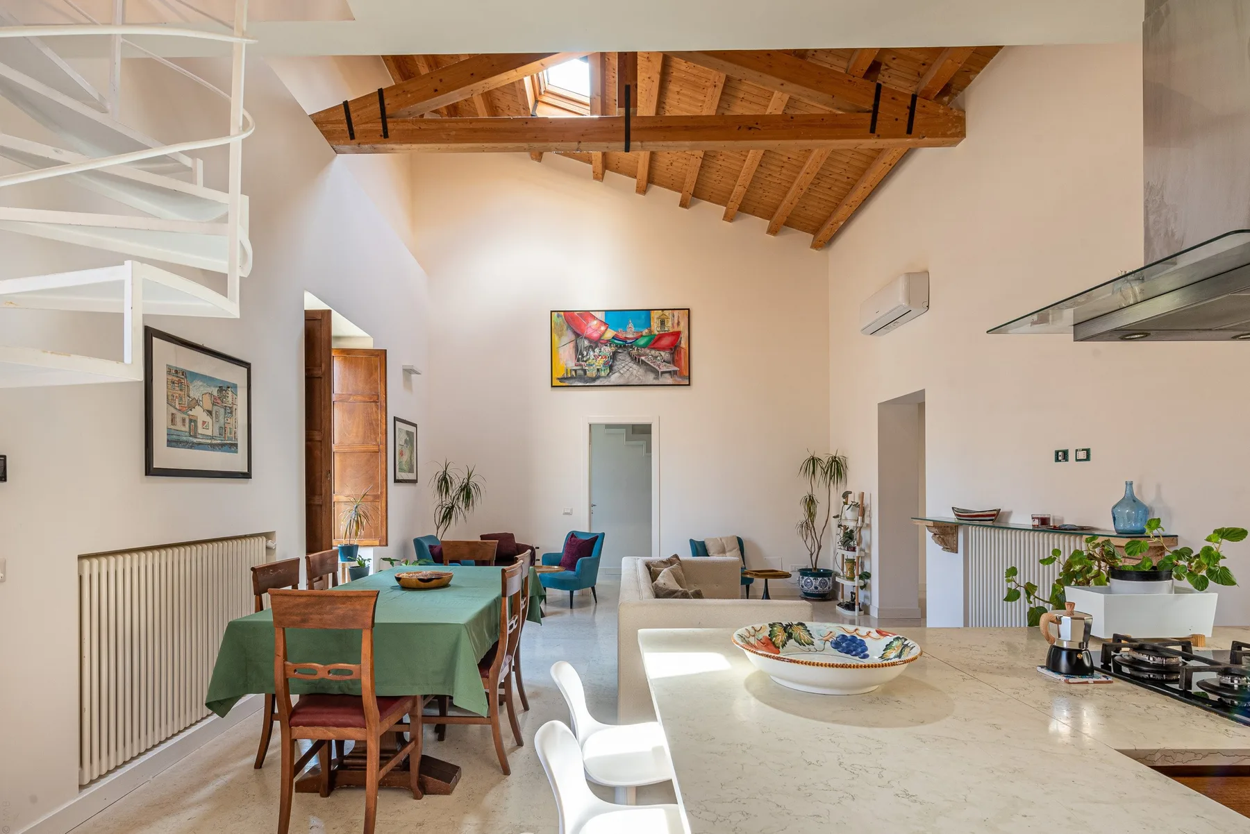 An open-plan dining and kitchen area beneath a high timber ceiling.