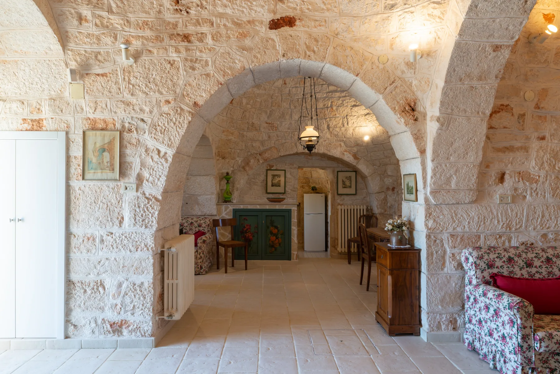 Una habitación interior de piedra con arcos, asientos y un mueble de madera.