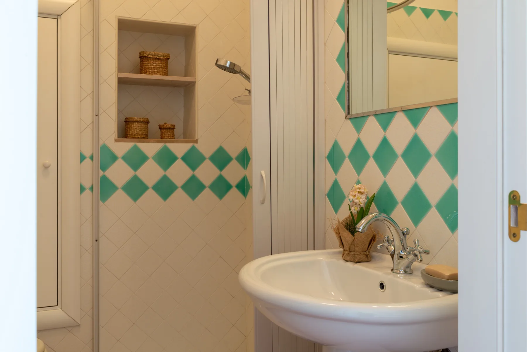 Un baño con azulejos, un lavabo y estantes empotrados en la pared.