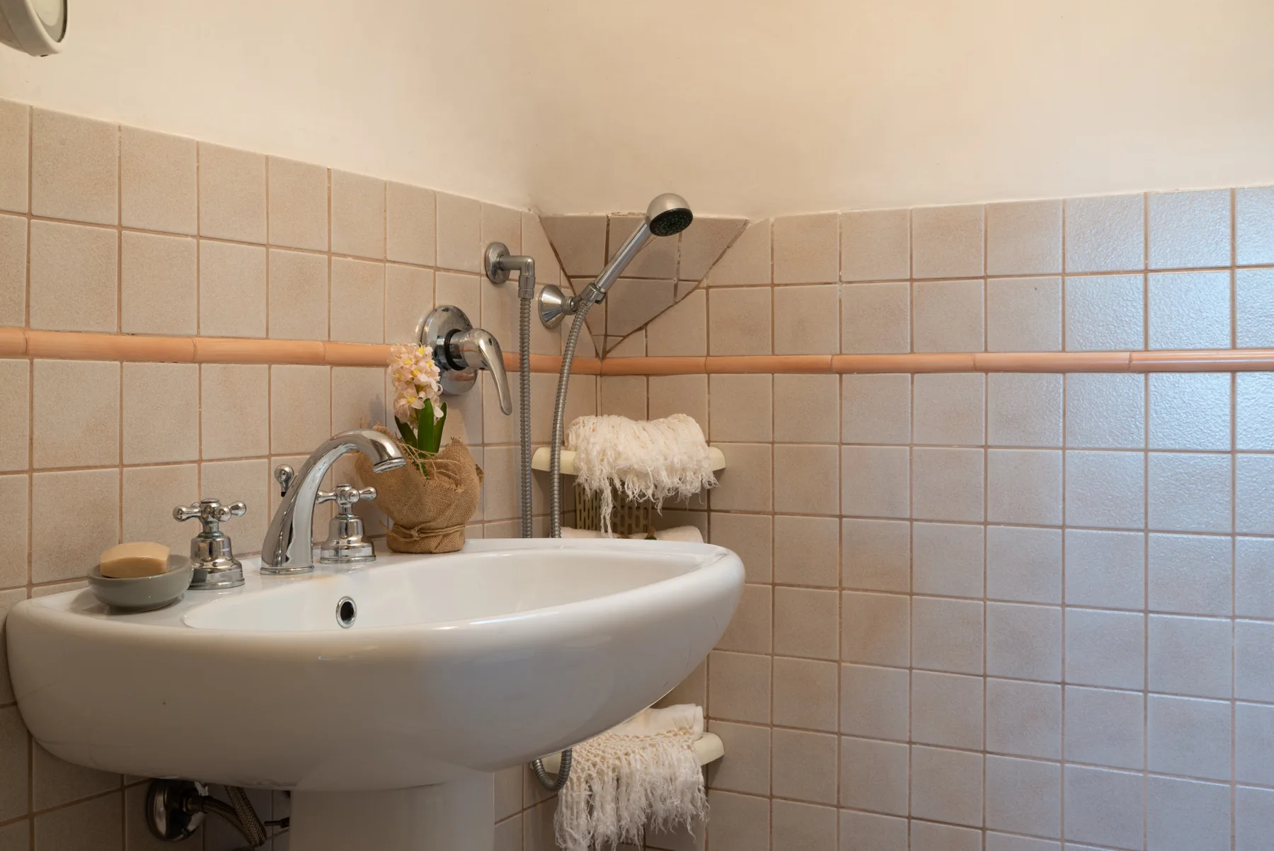 Un baño con azulejos, un lavabo blanco y una ducha de pared.