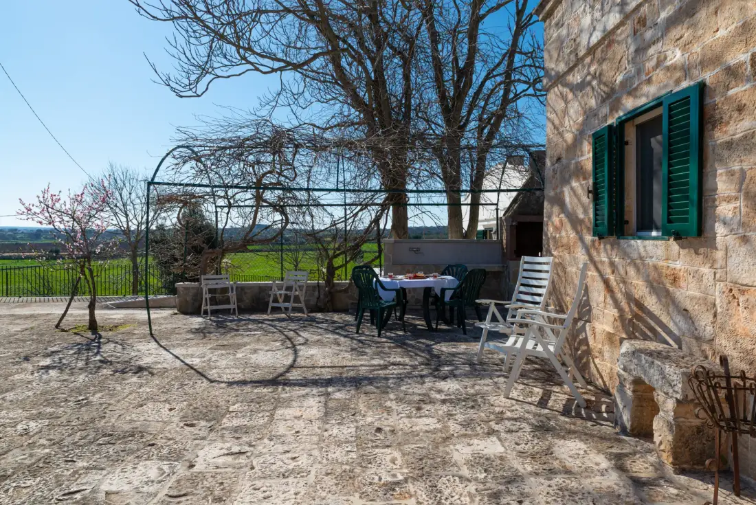 Un patio de piedra con asientos al aire libre y un árbol sin hojas junto al edificio.