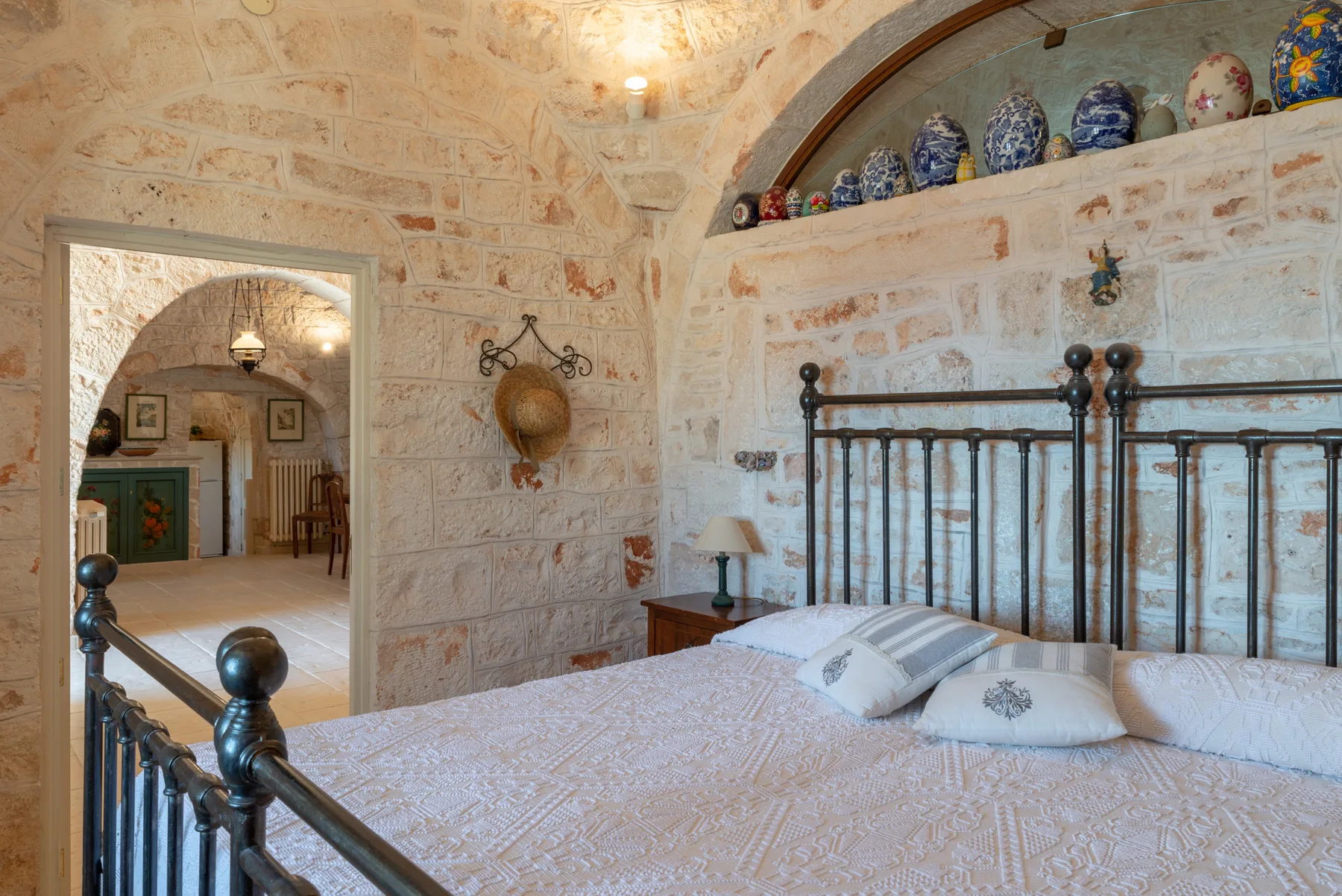 Un dormitorio con una cama bajo un nicho arqueado con cerámica decorativa.
