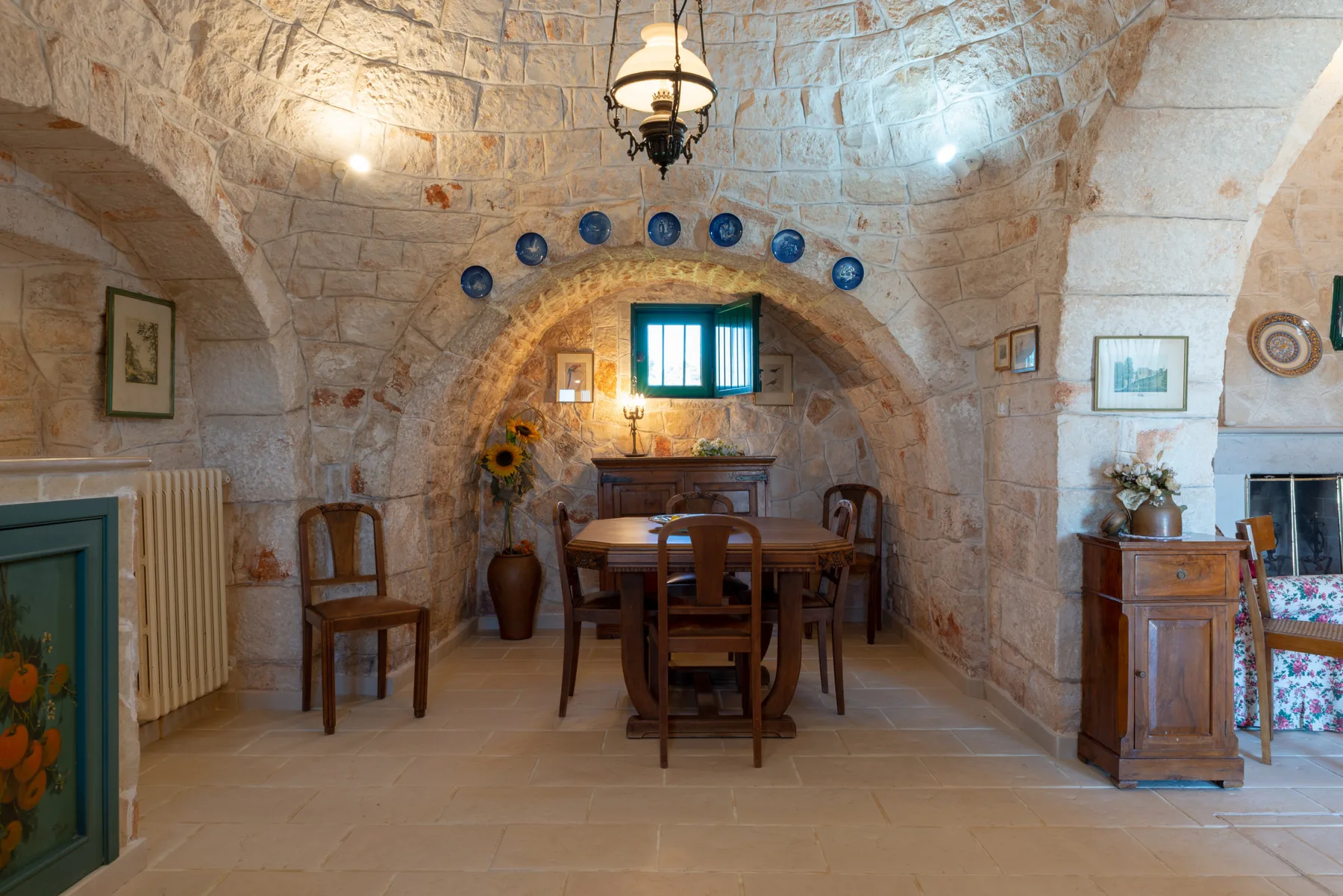 Un comedor de piedra con una mesa de madera bajo una ventana pequeña.