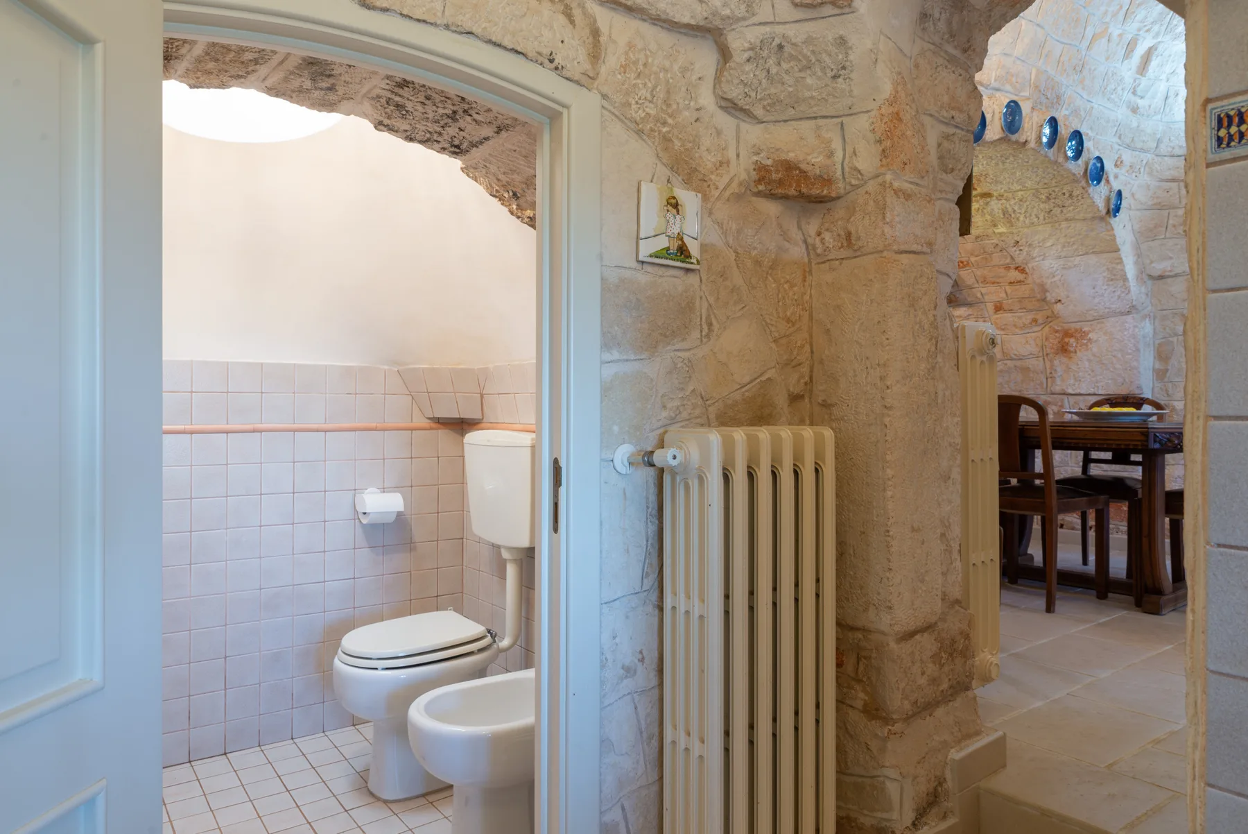 Un pasillo interior de piedra conecta un baño alicatado con un comedor.