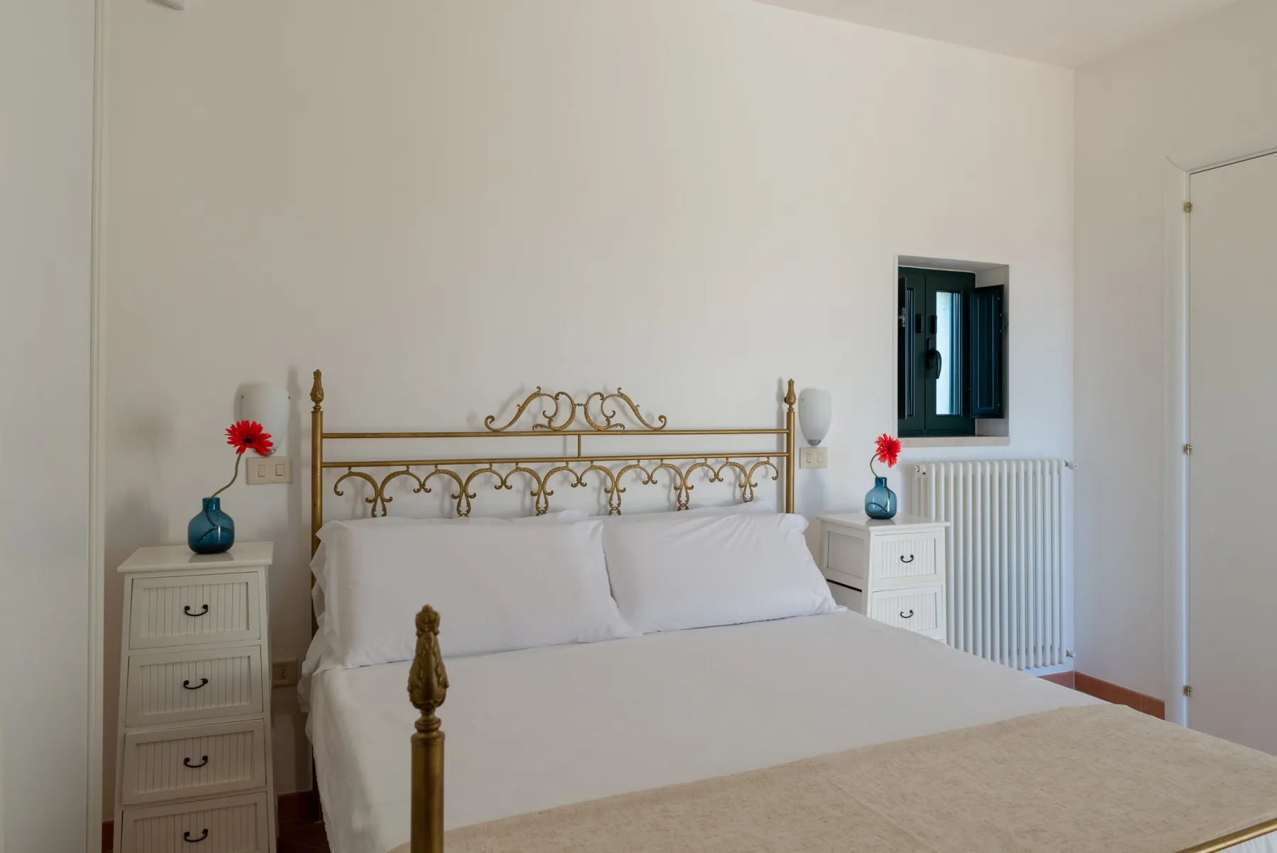 Un dormitorio con una cama doble, mesitas de noche y una ventana.