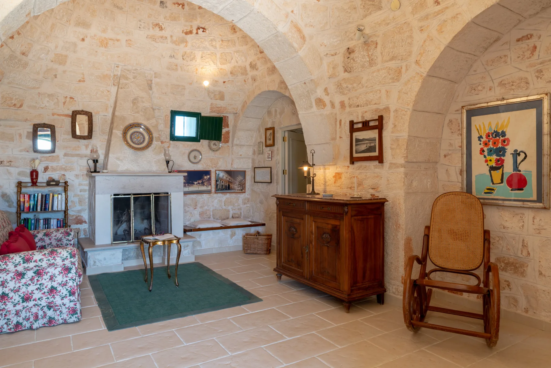 Sala de estar con bóvedas de piedra, chimenea, mueble de madera y asientos.
