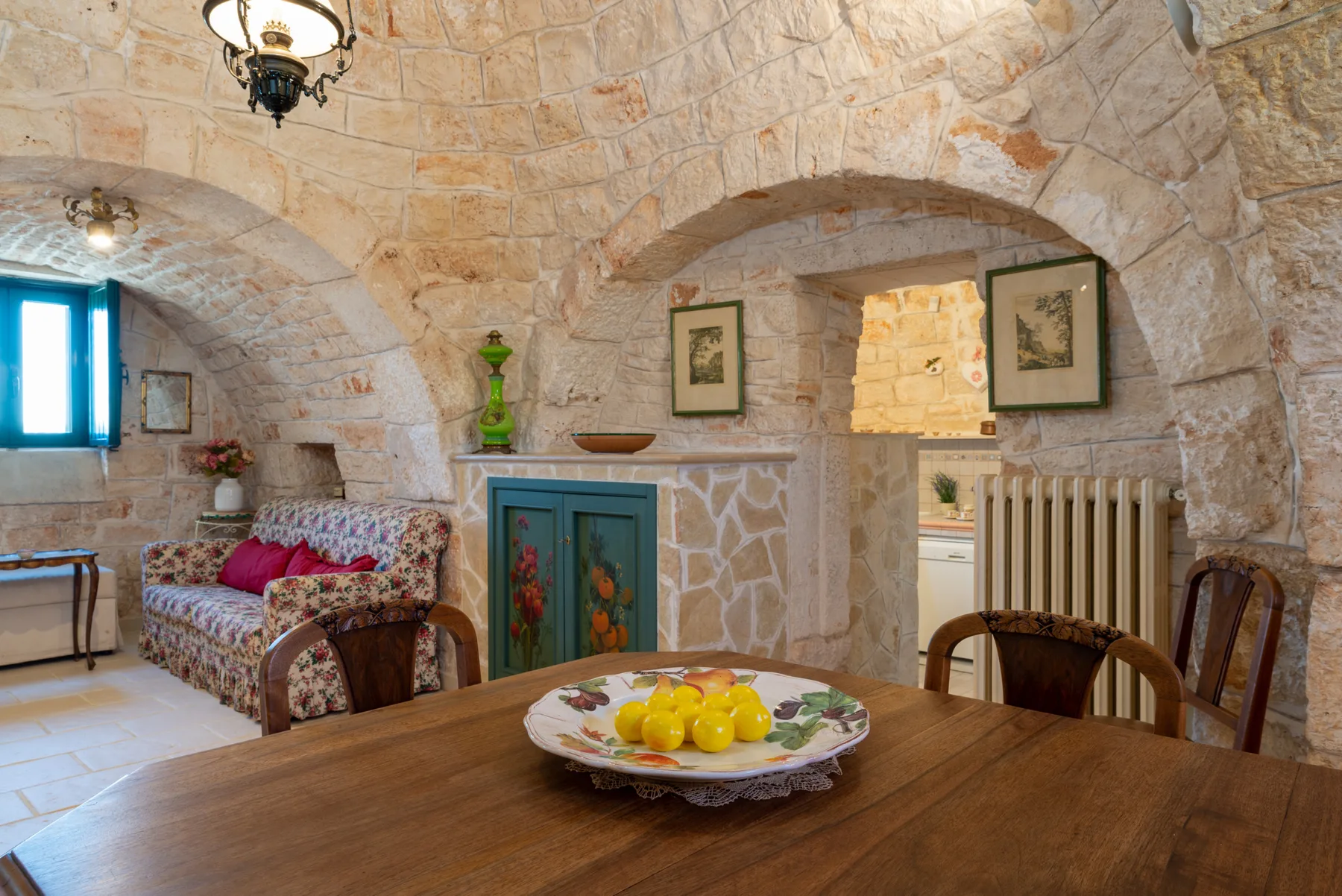 Una sala rústica de piedra con un sofá estampado y una mesa de comedor de madera.